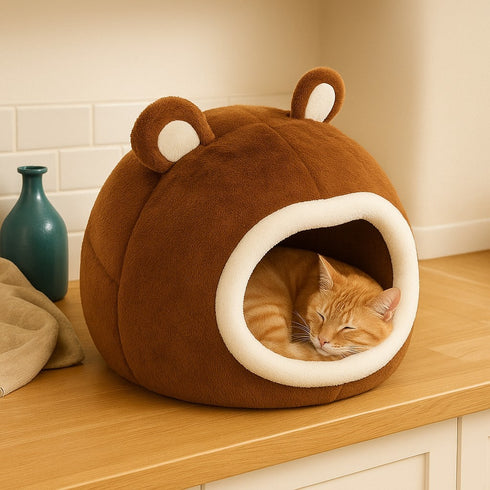 Panier boule pour chat en peluche marron avec chat endormi placé sur un plan de cuisine