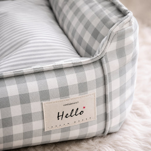 Gros plan sur un panier pour chat à carreaux gris avec tissu doux, finitions soignées et coussin confortable pour le repos quotidien.