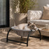 Chat allonge dans un panier chat design en tissu gris sur pied noir, installe sur une terrasse lumineuse au style moderne et chaleureux