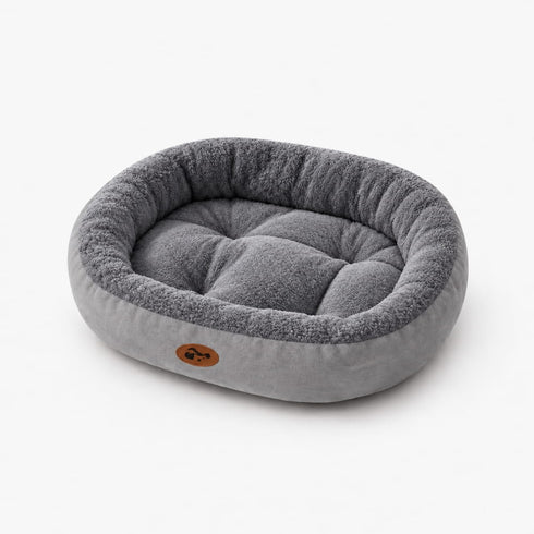 Panier douillet pour chat gris et écru en peluche, présenté seul sur fond blanc avec rebords moelleux et coussin intérieur matelassé.