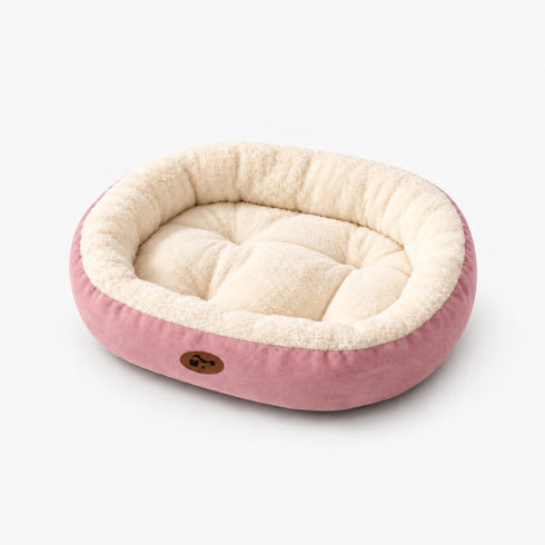Panier douillet pour chat rose et écru en peluche, présenté seul sur fond blanc avec rebords moelleux et coussin intérieur matelassé.