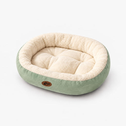 Panier douillet pour chat vert et écru en peluche, présenté seul sur fond blanc avec rebords moelleux et coussin intérieur matelassé.