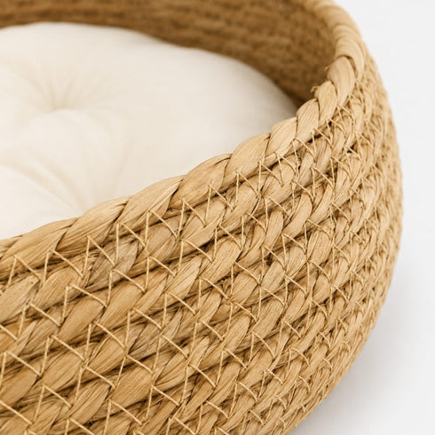 Gros plan sur un panier à chat imitation osier beige avec tressage détaillé et coussin crème moelleux pour un confort élégant.