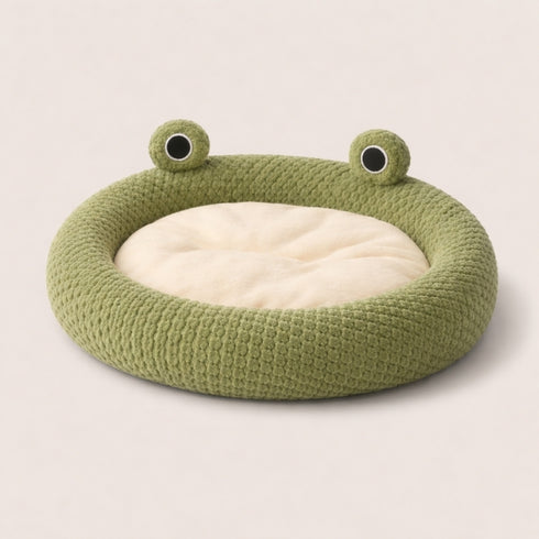 Panier pour chat Chat Cocooning en peluche verte avec coussin beige, forme ronde originale avec yeux décoratifs, idéal pour un coin cosy au salon.