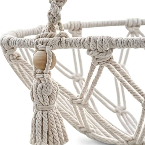Gros plan sur les cordes tressées et les perles en bois d’un panier pour chat suspendu en macramé au style bohème naturel.