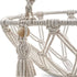 Gros plan sur les cordes tressées et les perles en bois d’un panier pour chat suspendu en macramé au style bohème naturel.