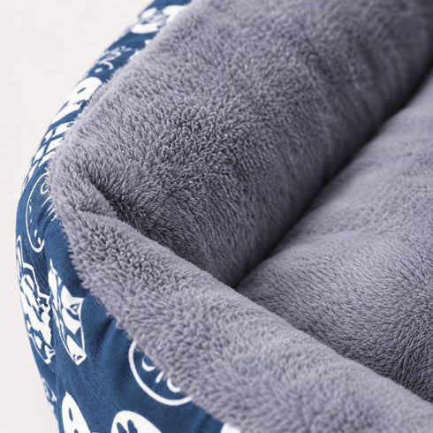 Gros plan sur un panier chaud pour chat bleu avec revêtement en peluche grise ultra douce et rebords confortables rembourrés.