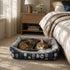 Chat tigré reposant dans un panier chaud pour chat bleu et gris, placé au pied d’un lit dans une chambre cosy et apaisante.