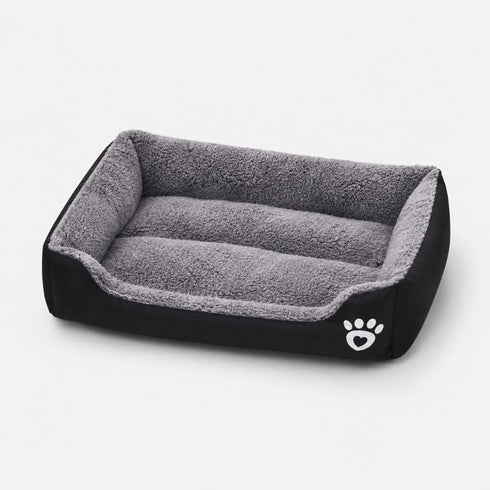 Panier chauffant pour chat noir et gris avec rebords rembourrés et surface douce, idéal pour offrir un couchage chaud et confortable.