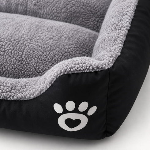 Gros plan sur un panier chauffant pour chat noir et gris avec texture peluche douce, rebords rembourrés et finition confortable.