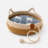 Panier en rotin pour chat en imitation rotin bicolore avec corde de jeu intégrée et coussin bleu à motifs, présenté sur fond neutre gris clair.