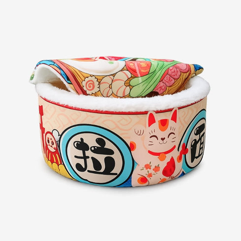 Panier fermé pour chat rond en tissu multicolore motif japonais, bordure en peluche blanche, photographié en studio sur fond blanc.