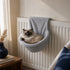 Panier radiateur pour chat en tissu peluche gris clair, suspendu sur un chauffage pour offrir un couchage chaud et confortable en hiver.
