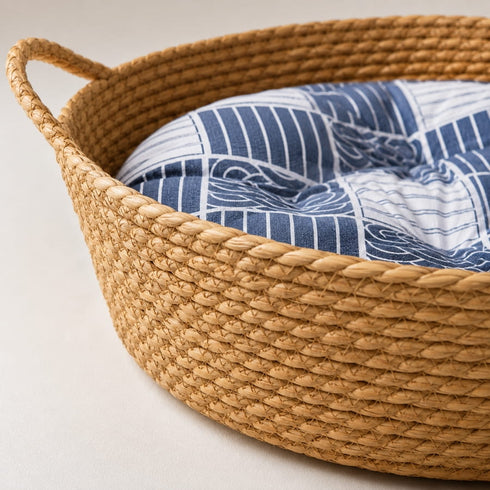 Gros plan sur un panier rond osier chat imitation osier avec tressage naturel et coussin bleu à motifs confortables.