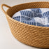 Gros plan sur un panier rond osier chat imitation osier avec tressage naturel et coussin bleu à motifs confortables.