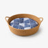 Panier rond osier chat imitation osier avec coussin bleu à motifs graphiques, conçu pour offrir un couchage confortable et élégant.