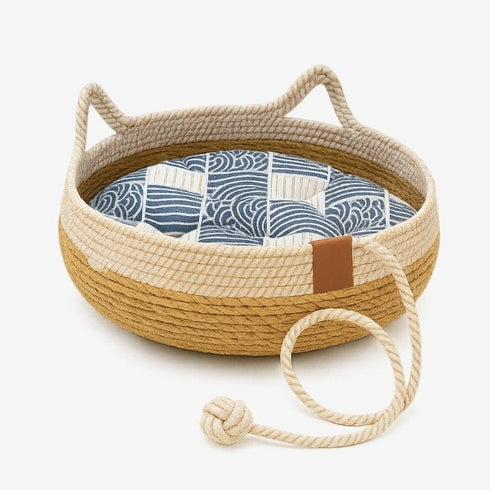 Panier en rotin beige avec coussin bleu à motifs, vue studio.