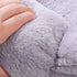 Zoom sur la texture douce du petit coussin pour chat en peluche gris clair, compressé à la main.