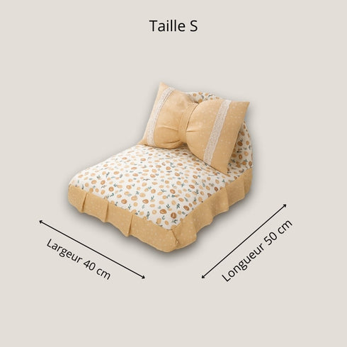 Petit lit pour chat taille S, coloris jaune à motif fruits, avec coussin en forme de nœud et jupe textile, dimensions 50 × 40 cm.