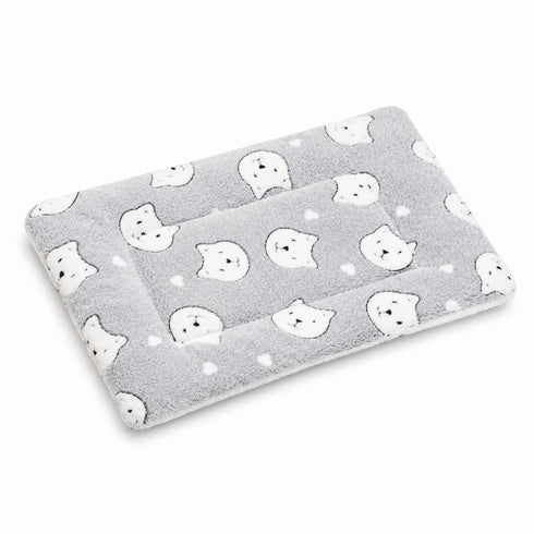 Petit tapis pour chat gris matelassé avec motifs têtes de chat et texture douce sur fond studio clair et minimaliste