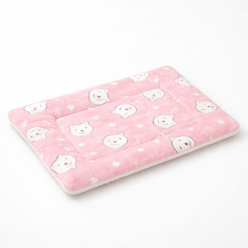 Petit tapis pour chat rose matelassé avec motifs têtes de chat et texture douce sur fond studio clair et minimaliste